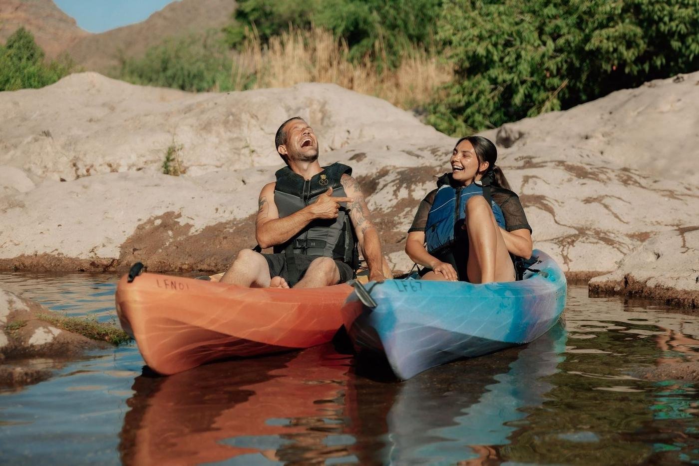 Two friends laughing in kayaks on the river